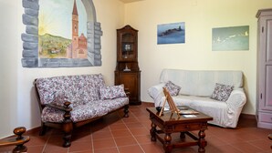A living room with two sofas, a wooden coffee table, a cabinet, and a painting of a church.