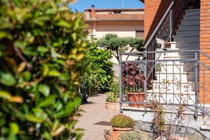 Un patio con plantas en macetas, una escalera y una reja de metal.