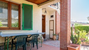 A patio with a table and chairs, a potted cactus, and a brick wall.