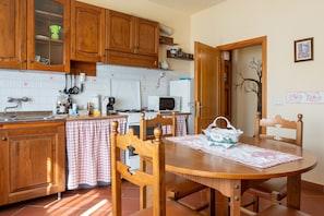 Una cocina con armarios de madera, un microondas, una estufa y una mesa de comedor con sillas.