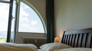 A hotel room with a large arched window, a bed with white bedding, a wooden headboard, and a bedside lamp. - Lovely apartment for 4 guests with WIFI, TV and patio (Strobl)