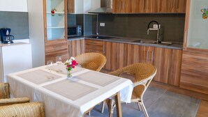 A compact kitchen with wooden cabinets, a microwave, and a stainless steel range hood. - Lovely apartment for 4 guests with WIFI, TV and patio (Strobl)