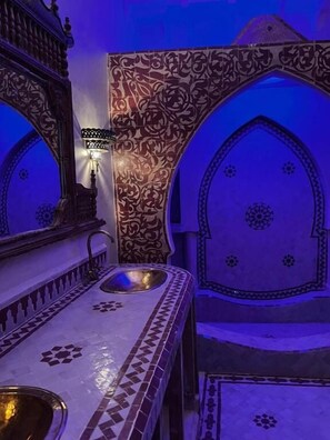 Un baño con detalles de azulejos elaborados, un lavabo y un espejo.