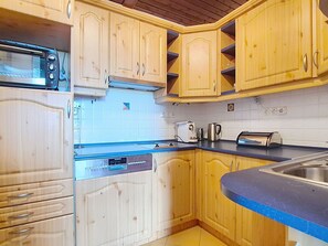 A kitchen with wooden cabinets, a microwave, a Siemens dishwasher, and a sink.