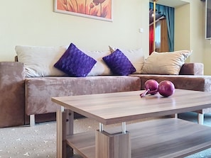 A living room with a sofa, cushions, a coffee table, and a painting on the wall. - Cosy apartment for 4 people with WIFI, TV and balcony (Strobl)