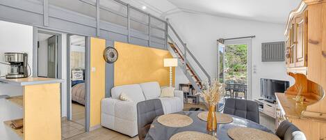 A modern interior with a dining area, sofa, staircase, and kitchen.