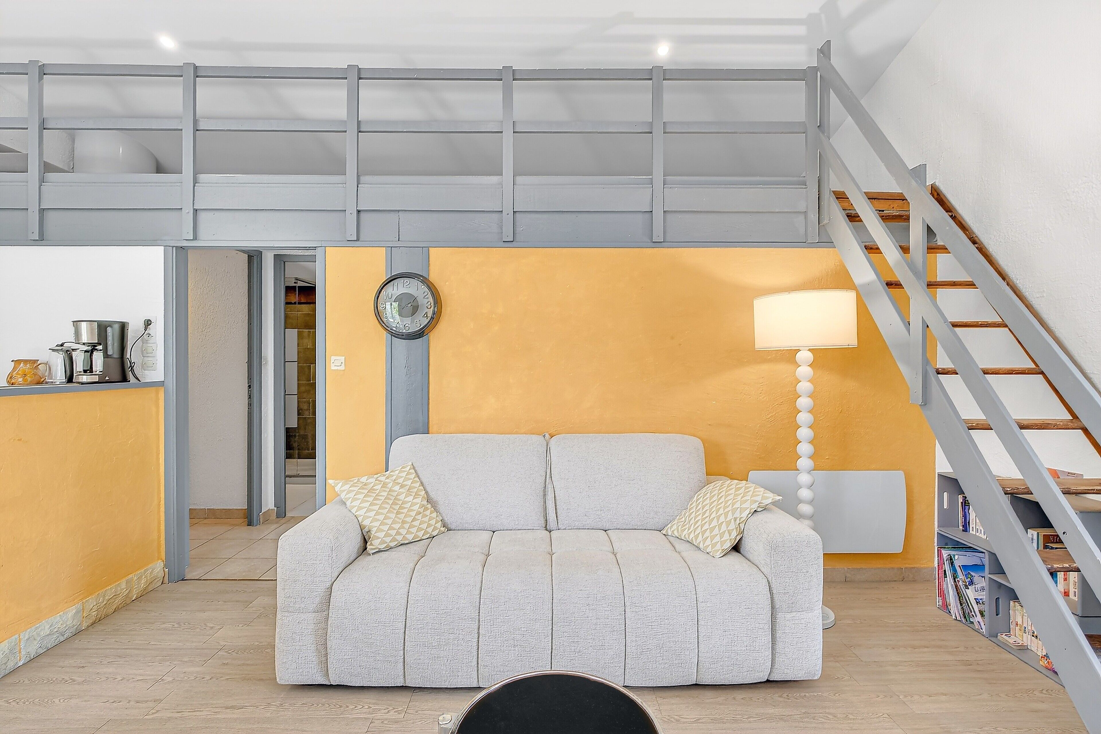 Un salon moderne avec un canapé, une lampe et un escalier.