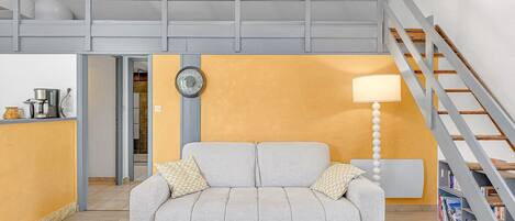 Un salon moderne avec un canapé, une lampe et un escalier.