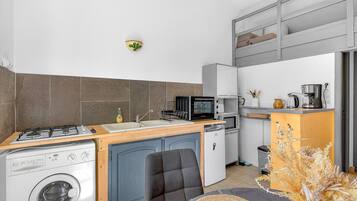 Eine kompakte Küche mit Waschmaschine, Mikrowelle und kleinem Kühlschrank.