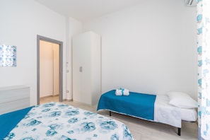 Une chambre avec deux lits, une armoire et une porte donnant sur une autre pièce.