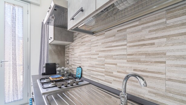 A modern kitchen with a gas stove, stainless steel sink, and a tiled backsplash. - Apartment 'Perla  2' with Shared Terrace, Wi-Fi and Air Conditioning (Pachino)