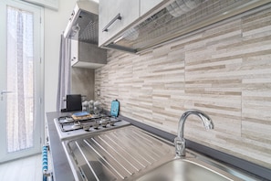 A modern kitchen with a gas stove, stainless steel sink, and a tiled backsplash. - Apartment 'Perla  2' with Shared Terrace, Wi-Fi and Air Conditioning (Pachino)