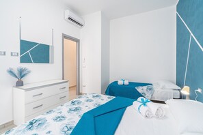 A hotel room with a bed, a dresser, a mirror, and an air conditioning unit.