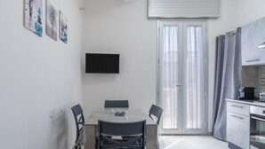 Moderni keittiö, jossa on ruokailutila, taulutelevisio ja liukuovet, jotka ovat lasia.