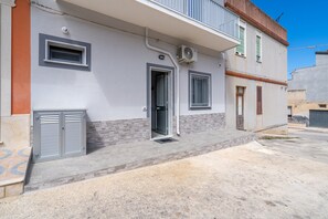 A residential building with a front door, two windows, and an air conditioning unit.