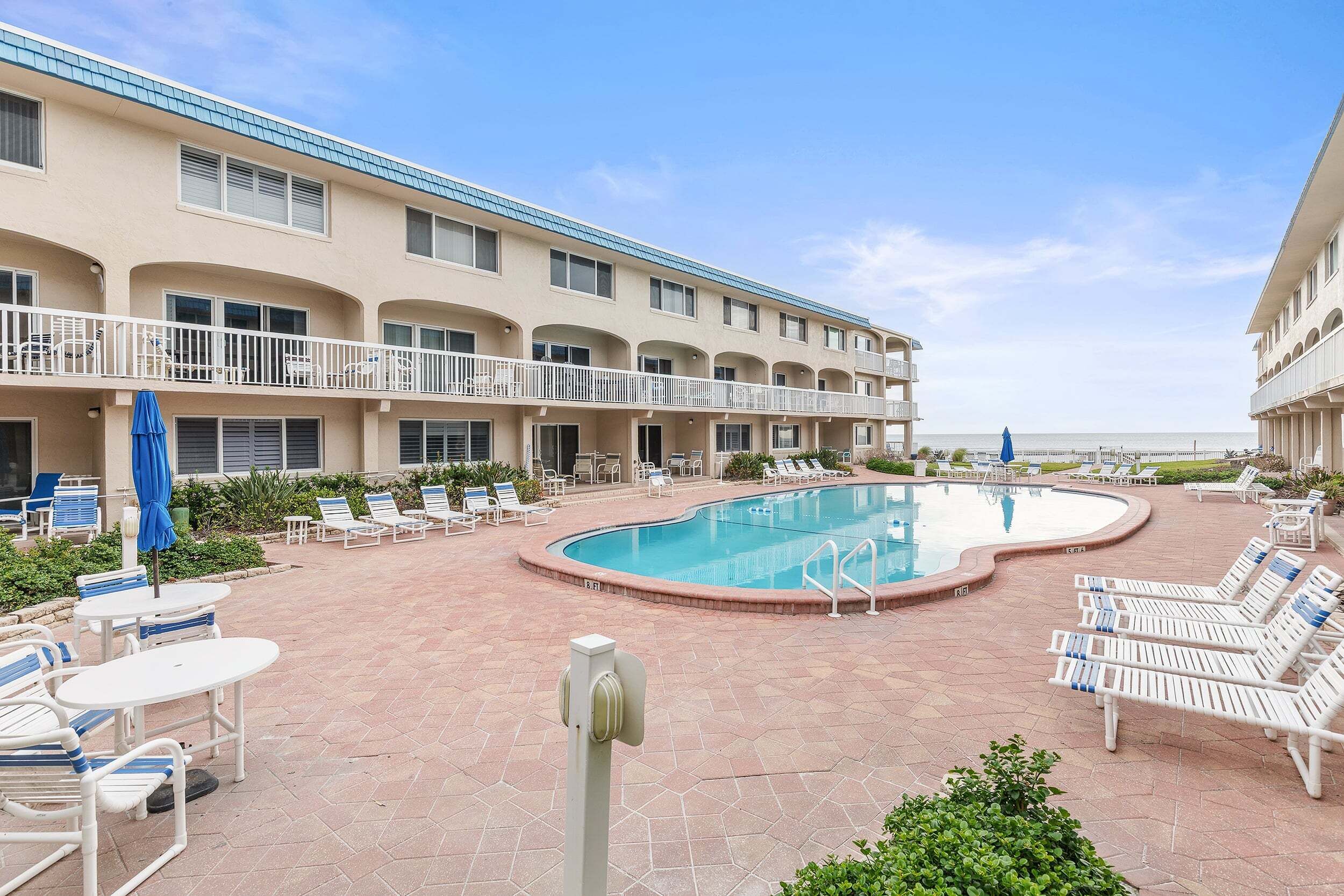 A hotel with a swimming pool, outdoor seating, and a view of the ocean.