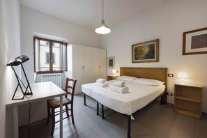 Een hotelkamer met een bed, een bureau, een stoel, een lamp en een raam.