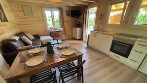 Ein gemütliches Blockhaus-Interieur mit Essbereich, Sofa, Küche und großen Fenstern.