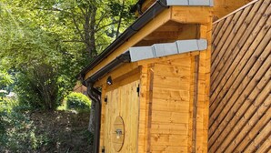 Eine Holzhütte mit geneigtem Dach, einer runden Tür und Kiesgrund.