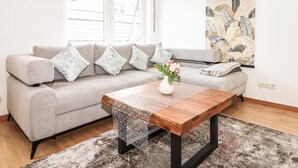 Ein modernes Wohnzimmer mit grauem Sofa, einem Holztisch und einer Wanddekoration.