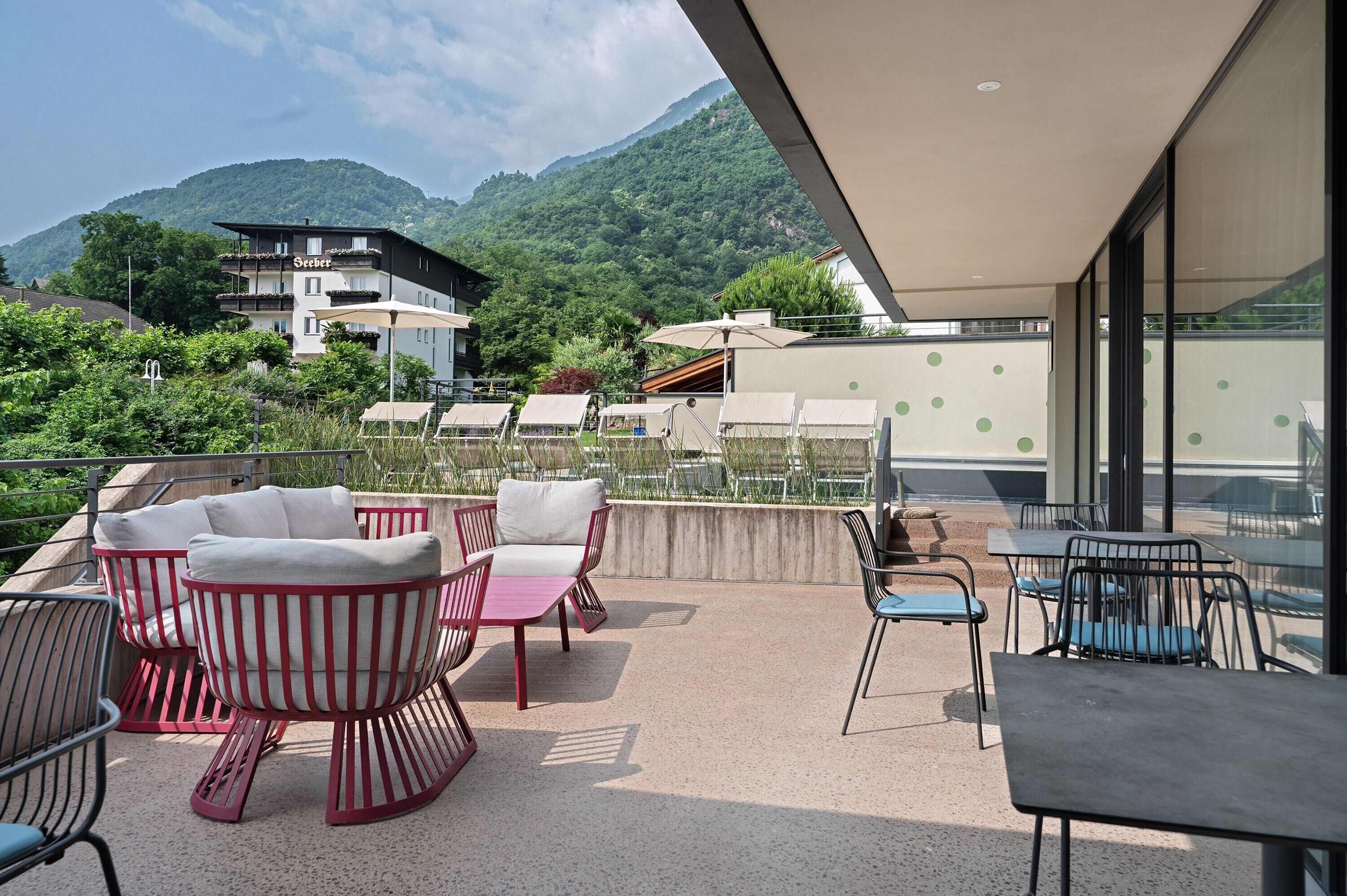 A terrace with outdoor seating, a mountain view, and a building with balconies.