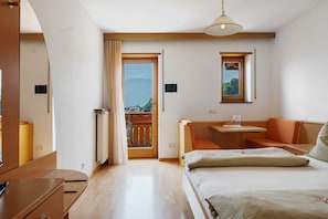 Un dormitorio con cama, escritorio, silla, una mesita y balcón con vistas.