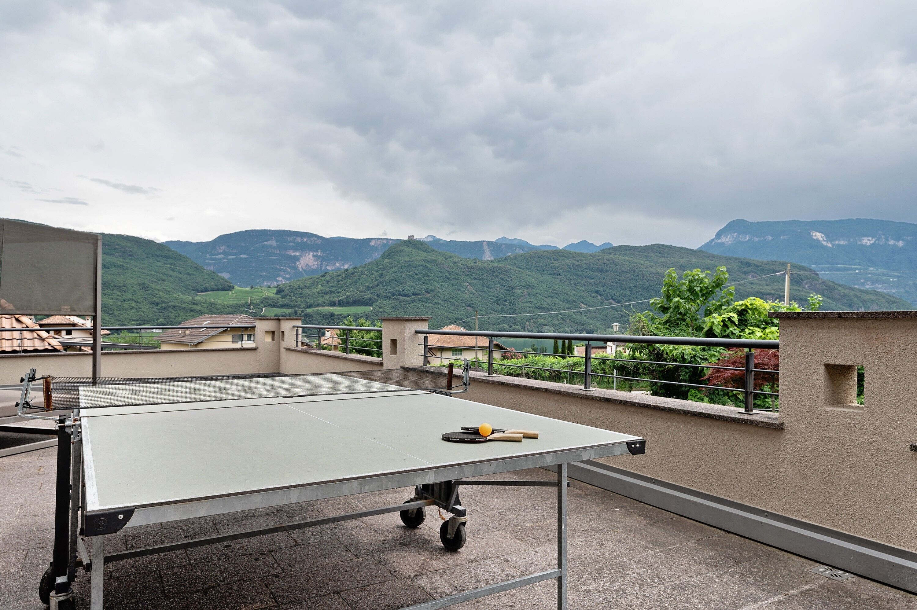 A ping pong table on a rooftop with a view of green hills and mountains.
