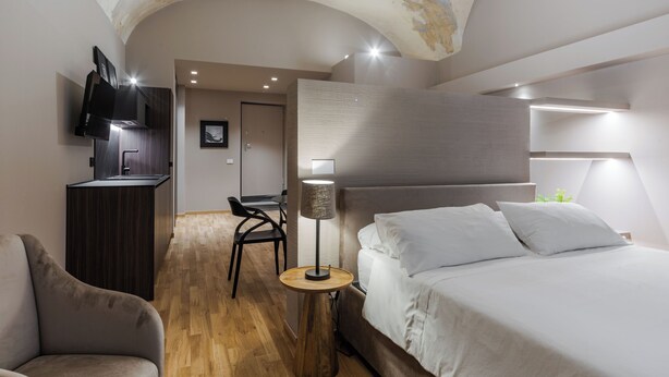 Una habitación de hotel moderna con una cama, un escritorio, una silla y un televisor montado en la pared.