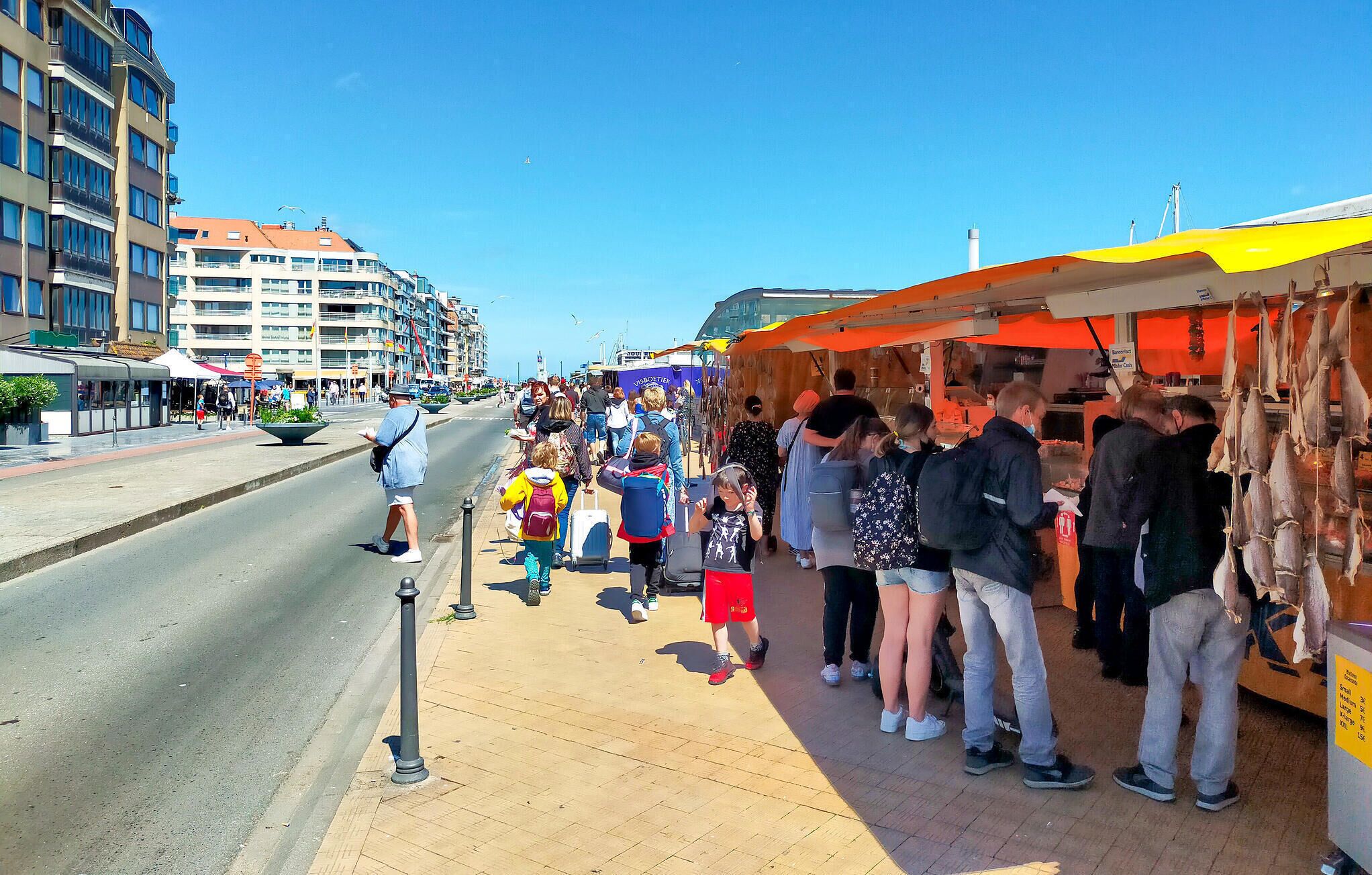 A busy street with people queuing at a food stall.