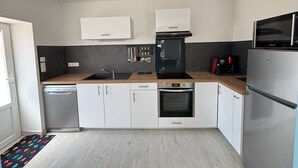 A modern kitchen with white cabinets, a black stove, and a stainless steel refrigerator.