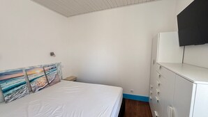 A bedroom with a bed, a dresser, and a wall-mounted TV.