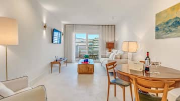 Ein modernes Hotelzimmer mit Essbereich, einer Couch, einem Couchtisch und einem Balkon mit Aussicht.