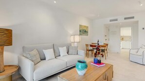 A modern living room with a sofa, coffee table, and dining area.