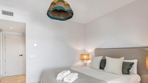 A bedroom with a bed, a bedside lamp, and a hanging light fixture.