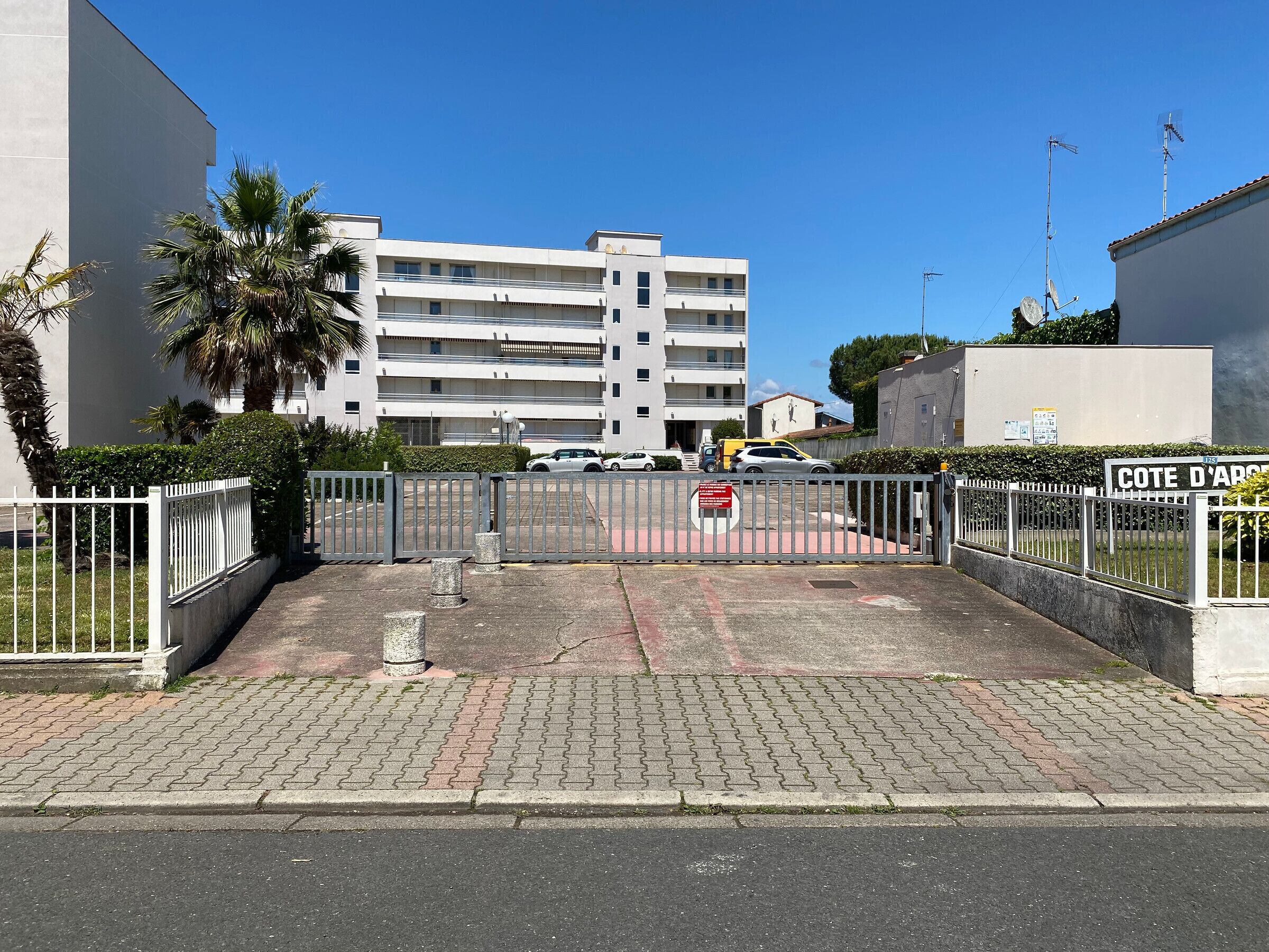 A gated parking area with a building in the background.