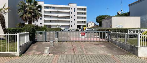 A gated parking area with a building in the background.