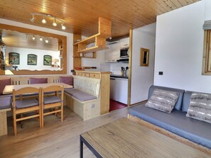 A cozy interior with a wooden dining table, benches, a sofa, and a kitchenette. - 2* Apartment Méribel, South, Ski-in, 5 pers. (Méribel)