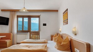 Une chambre d’hôtel avec deux lits, une télévision, une fenêtre donnant sur un paysage agréable et un balcon.