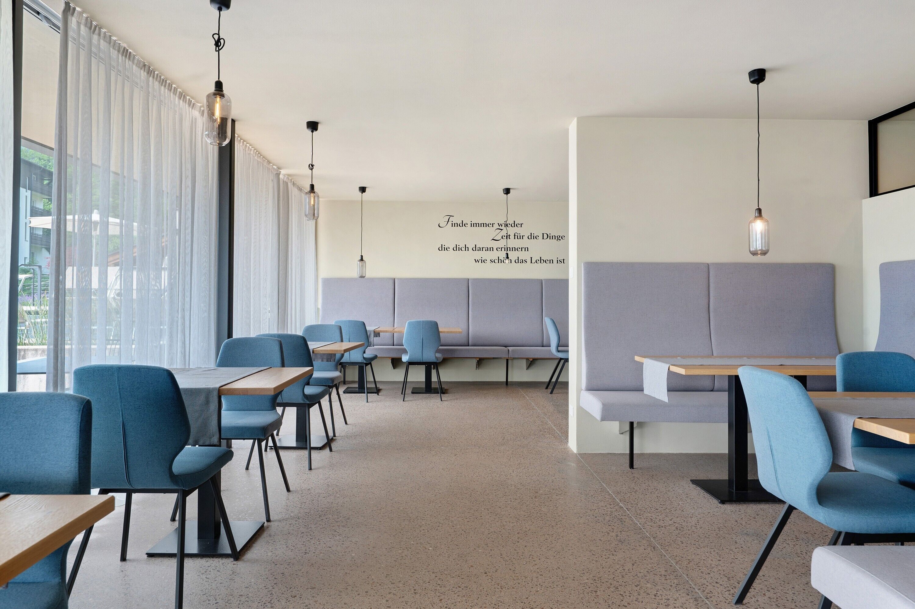 Ein modernes Interieur mit Sitzgelegenheiten, Tischen und Pendelleuchten.
