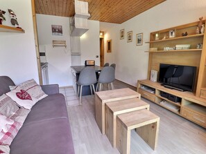 Uma sala de estar moderna com sofá, um rack para TV e um espaço de jantar com cadeiras.