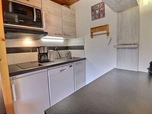 Cozinha compacta com armários brancos, micro-ondas, máquina de café e pia.