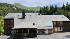 A two-story lodge with a covered patio and a mountain backdrop.