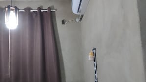 Une pièce dotée d’un ventilateur de plafond, d’un climatiseur, d’un rideau, d’une prise de courant et d’un multiprise.