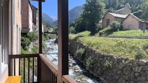 A balcony with a view of a river, stone wall, and houses in a mountainous area. - Renovated, balcony, Cauterets center (Cauterets)