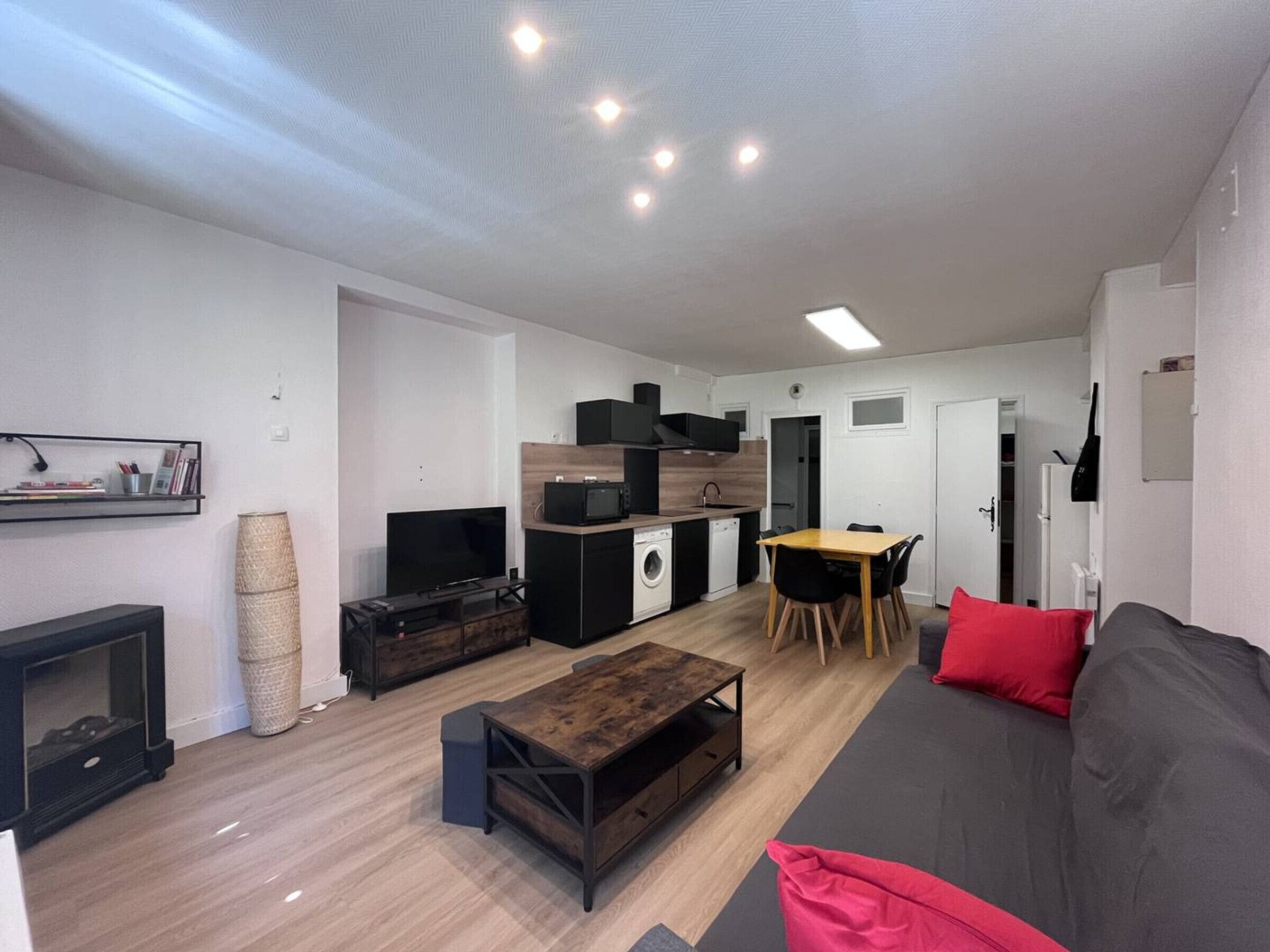 Un salon moderne comprenant un canapé, un téléviseur, une table basse et un coin repas avec des chaises.