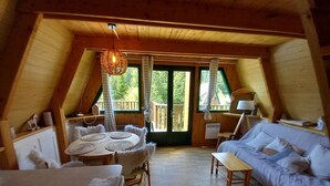 Una camera da letto mansardata accogliente con soffitto in legno, un tavolo rotondo con tovaglia bianca, un divano e un letto.