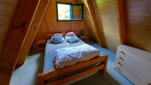 Una camera da letto mansardata accogliente, con un letto in legno, un comodino e una finestra.