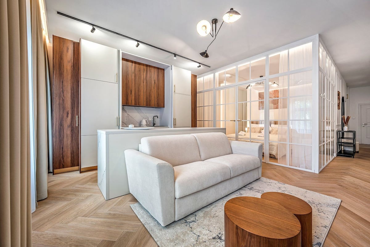 Un interior moderno con sofá, suelo de madera y zona de cocina.