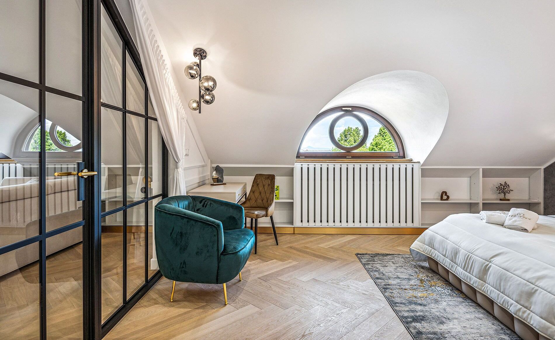 A bedroom with a sloped ceiling, a skylight, a bed, a chair, and a radiator.