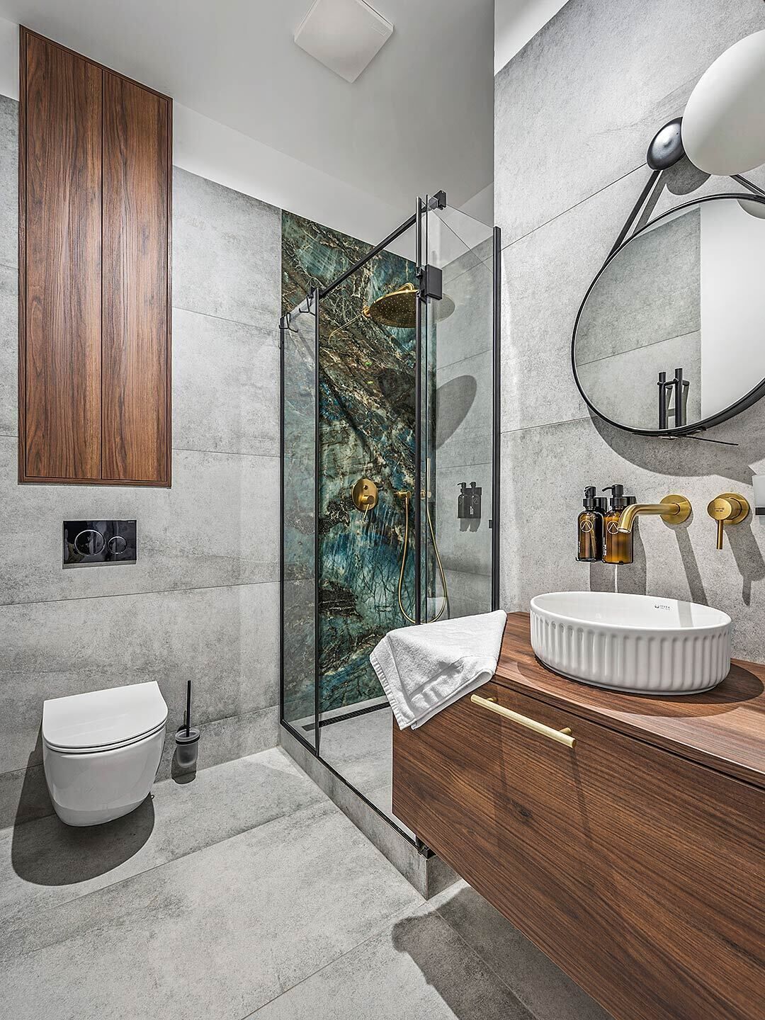 A modern bathroom with a glass-enclosed shower, a wooden vanity, and a marble backsplash.